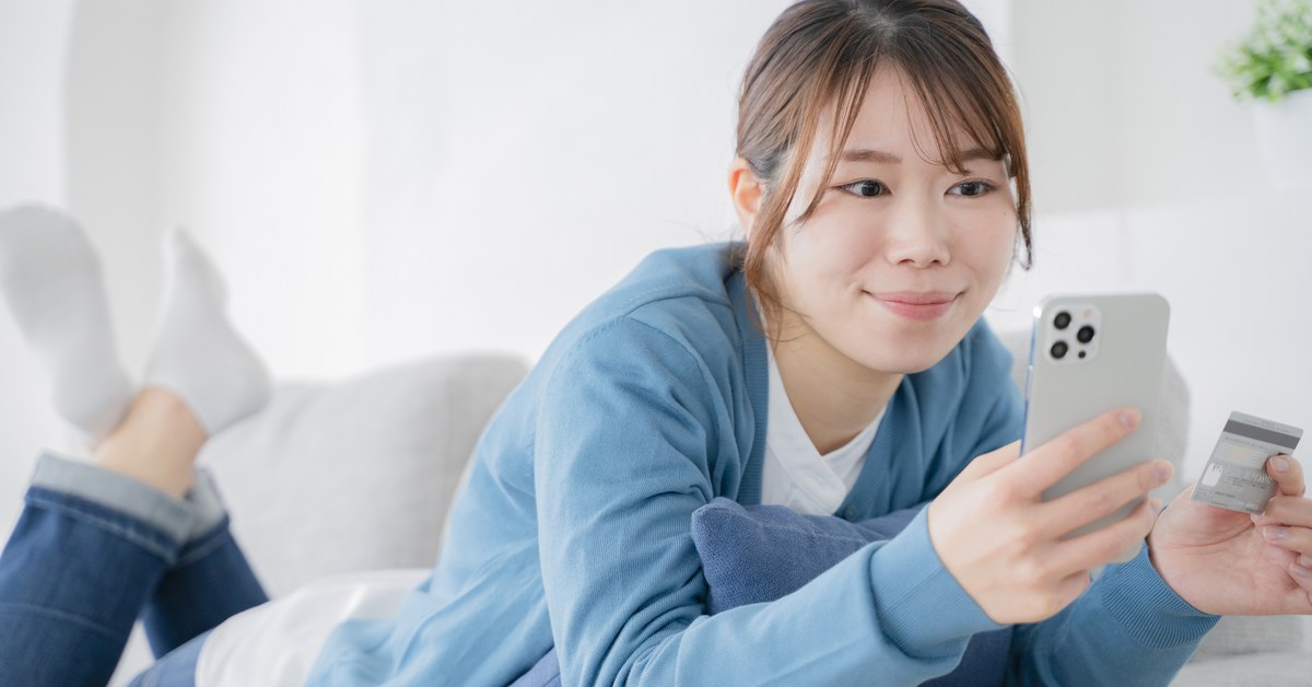 スマートフォンとカードを手に持つ女性