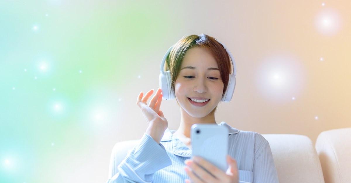ヘッドホンをつけてスマートフォンを見る女性