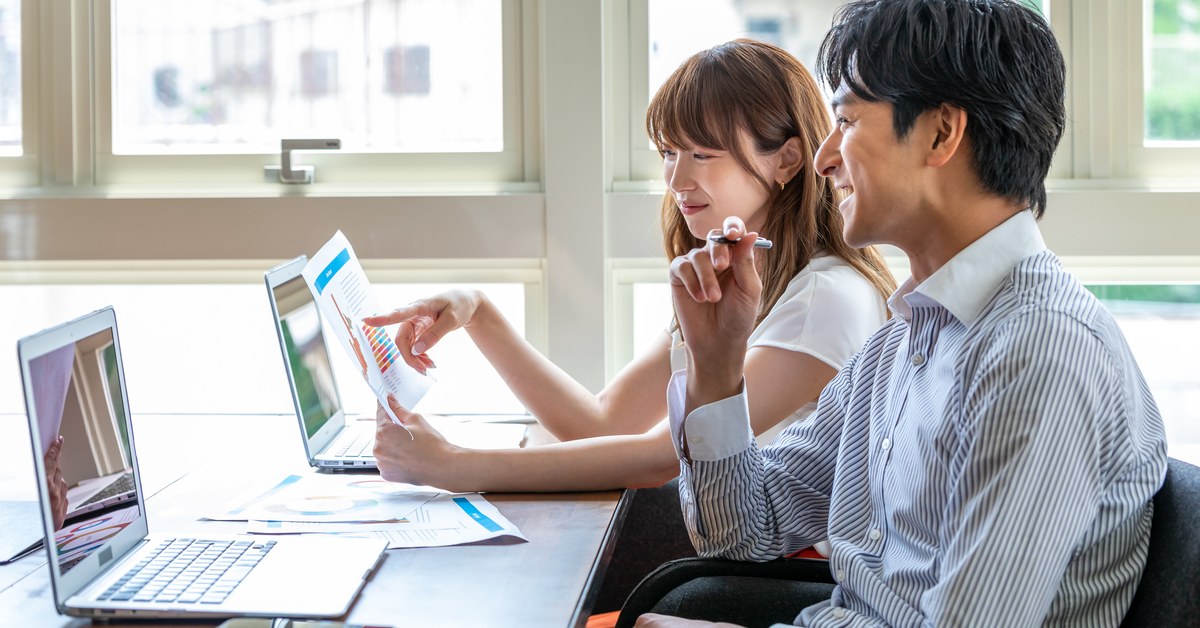 ノートパソコンと資料を見ながら料金プランを検討する二人