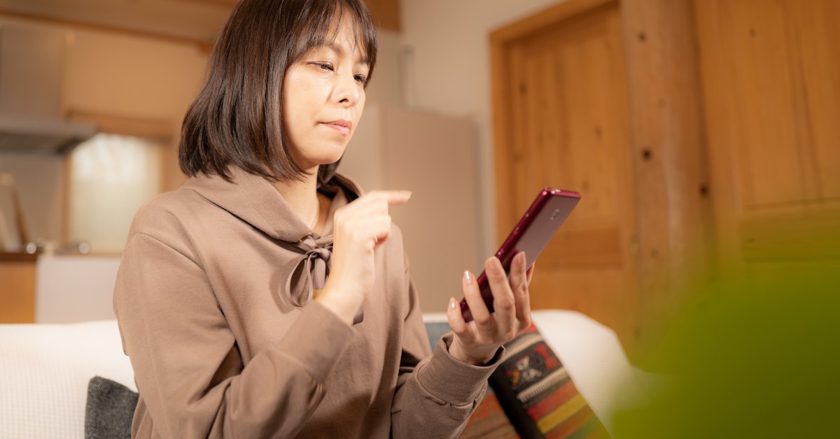 スマートフォンの画面を指差す女性