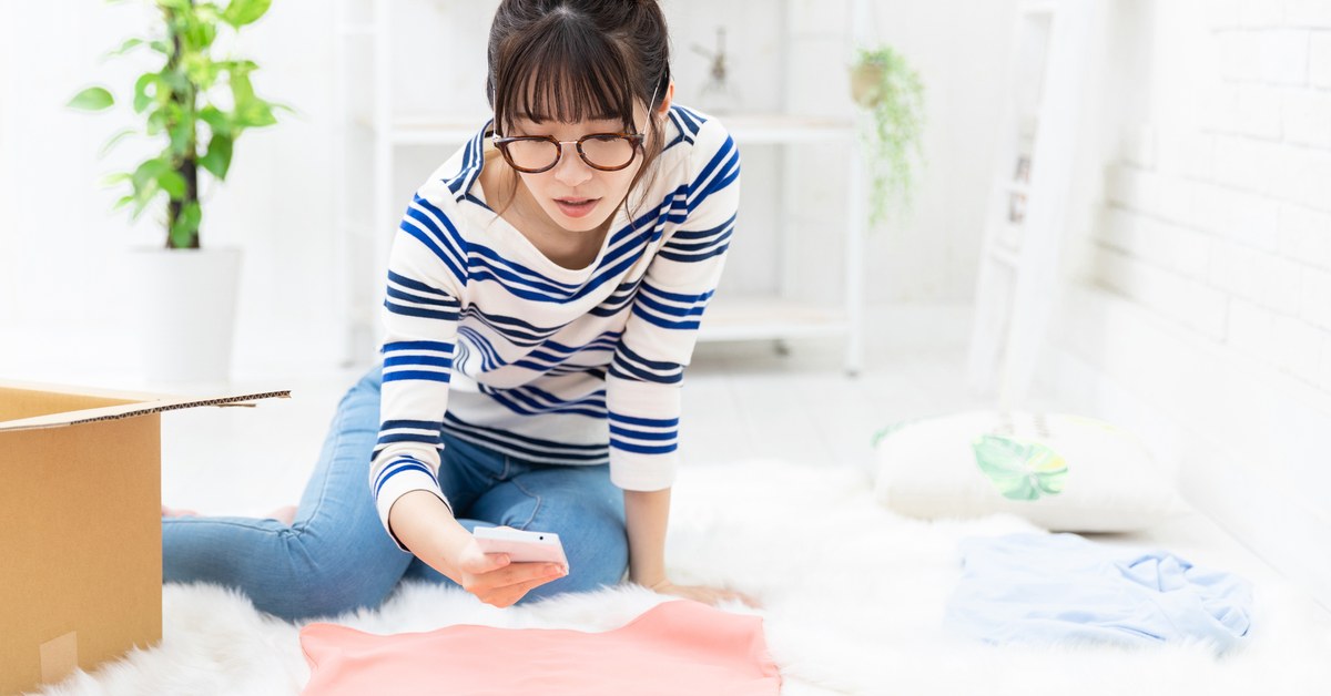 ネットで売る商品を段ボールに詰める準備をする女性