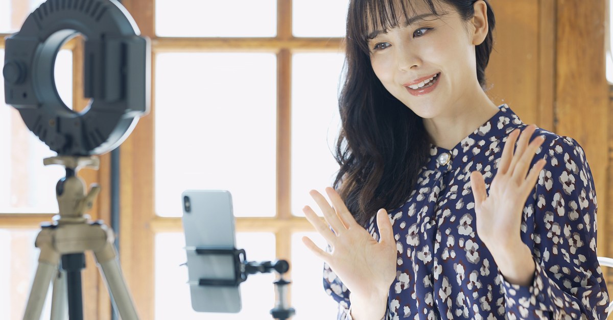 リングライトとスマートフォンを立てて配信する女性