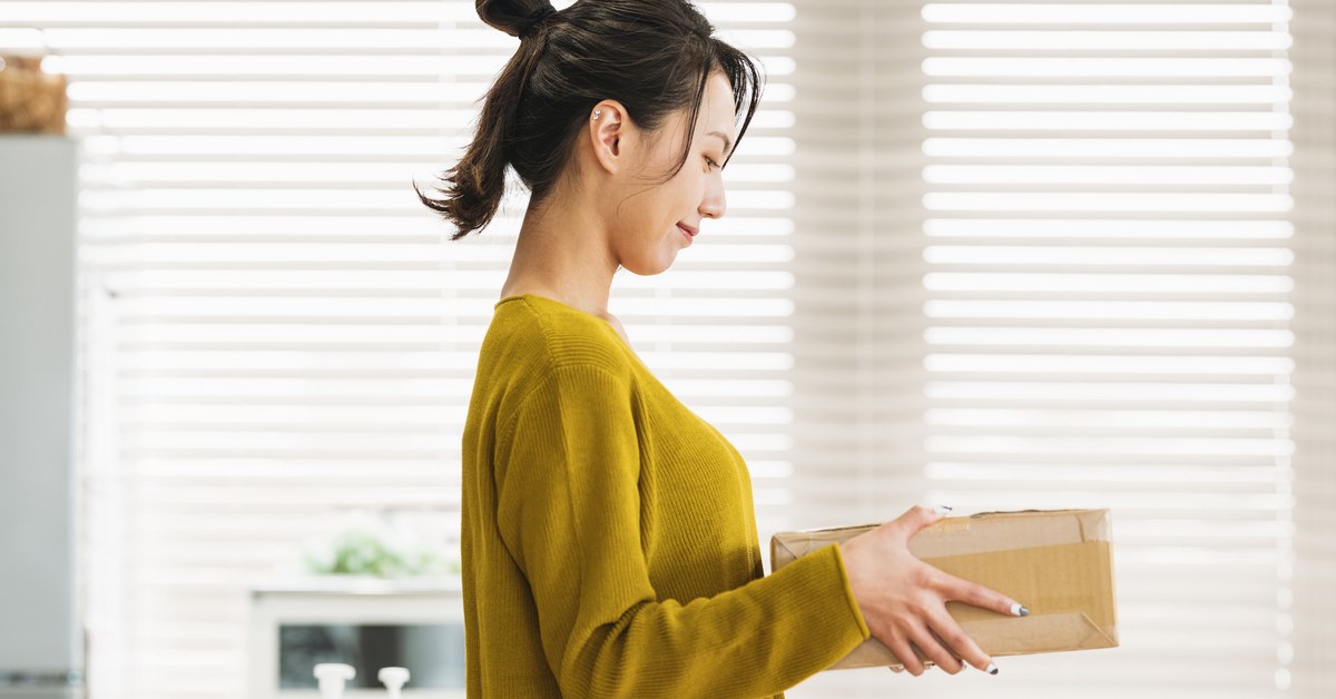 自宅で届いた段ボール箱を手に持つ女性