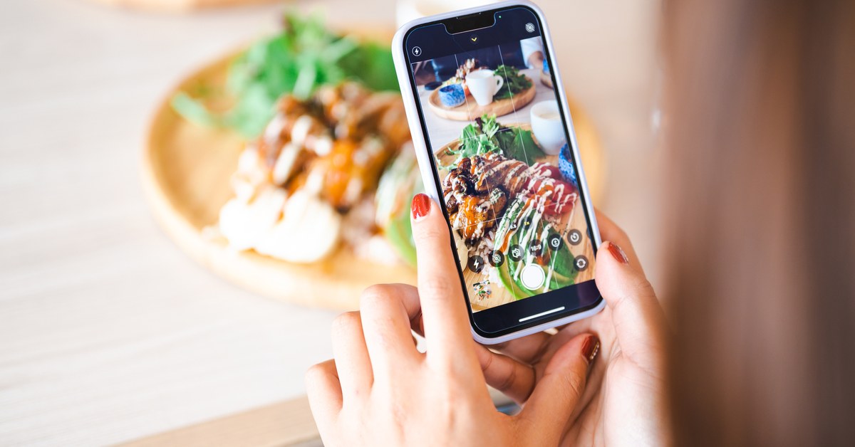 カフェで料理をスマートフォンで撮影する手元